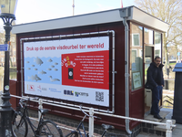 901601 Afbeelding van een banner met tekst en uitleg over de 'eerste visdeurbel' ter wereld, op de zijgevel van het ...